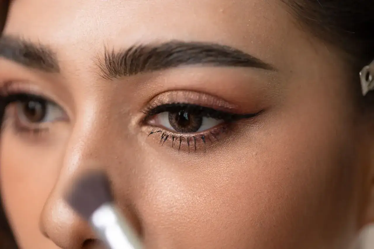 Ein Make-up-Pinsel n&auml;hert sich dem Auge einer Frau, um den perfekten Cat-Eye-Look zu kreieren.