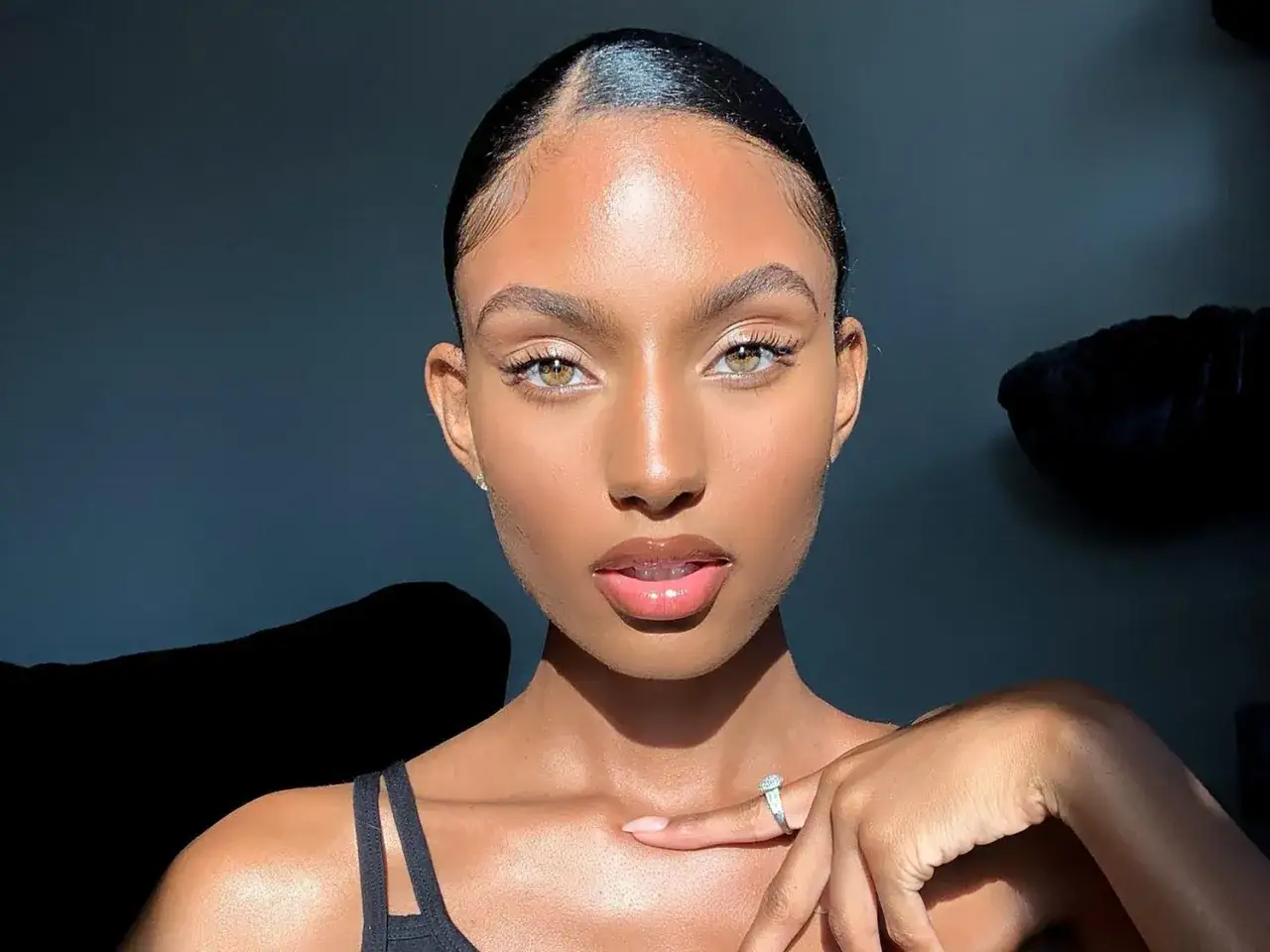 Ein Porträt einer jungen Frau mit strahlendem, glowy Make-up und einem glänzenden Lippenstift.