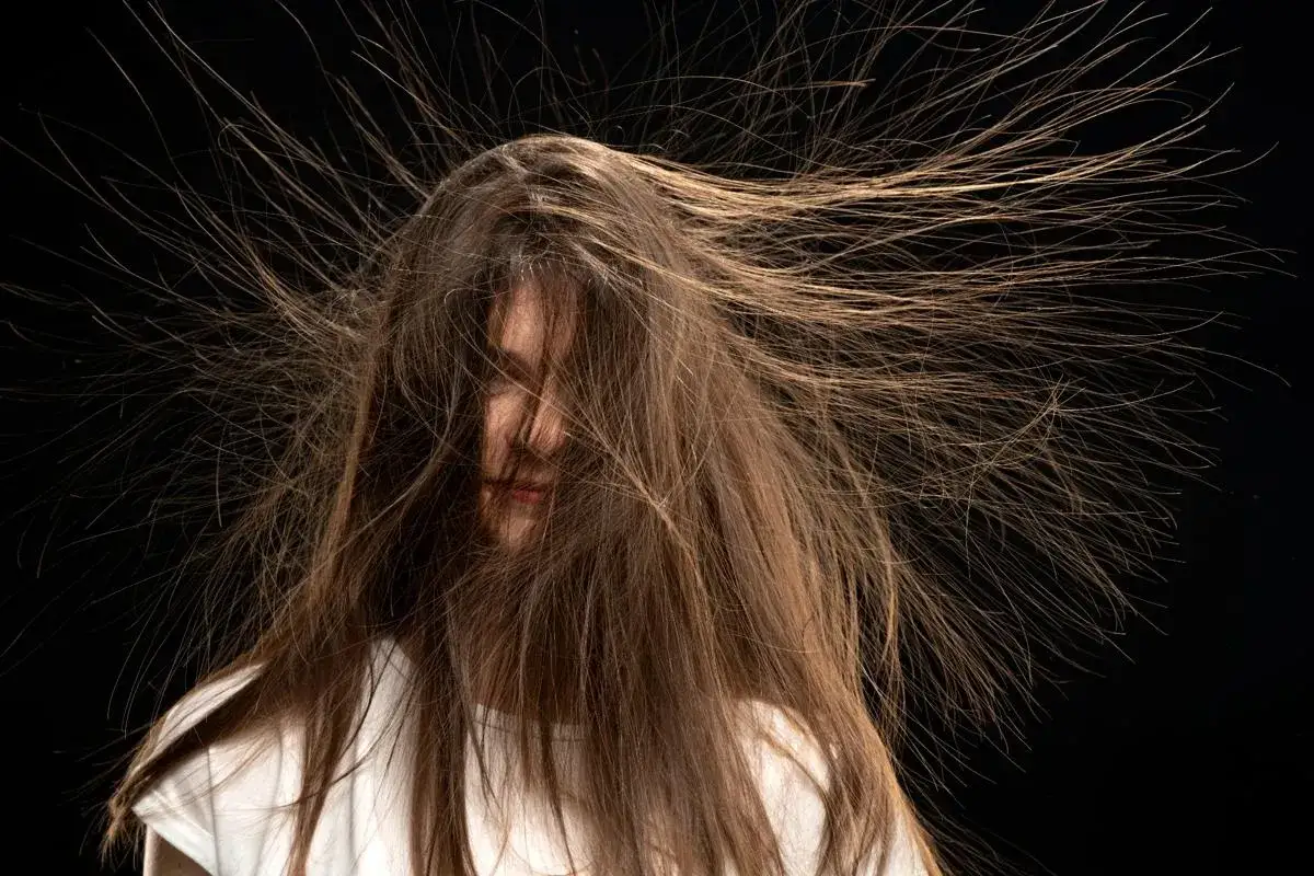 Ein Mädchen mit braunen, aufgeladenen Haaren, die wie ein Heiligenschein in alle Richtungen abstehen.