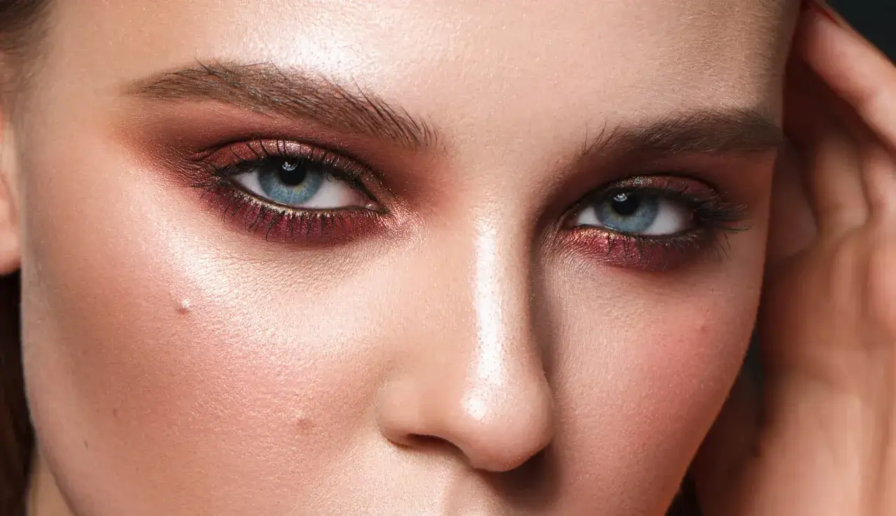 Intensives Make-up lässt die blauen Augen strahlen. Ein Hauch von Gold und Rot umrahmt sie.