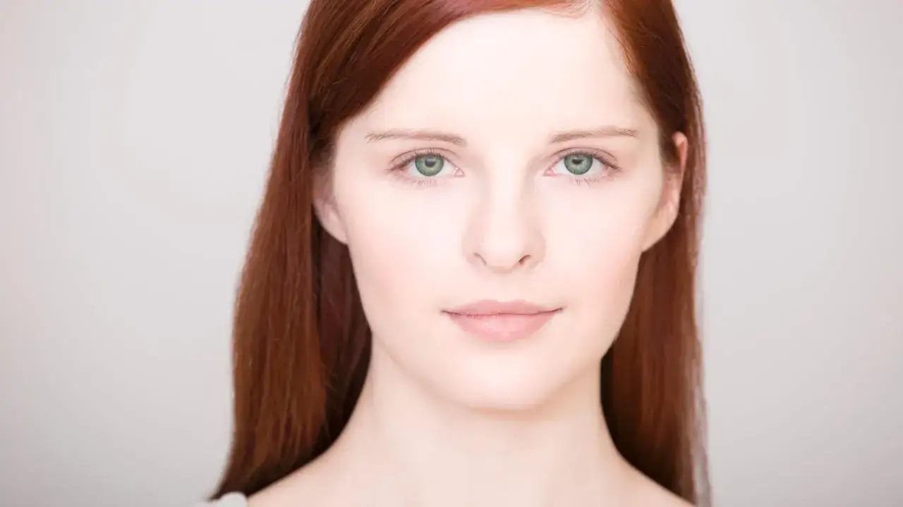 Portr&auml;t einer jungen Frau mit roten Haaren und einem blassen Gesicht, deren gr&uuml;ne Augen den Betrachter direkt ansehen.